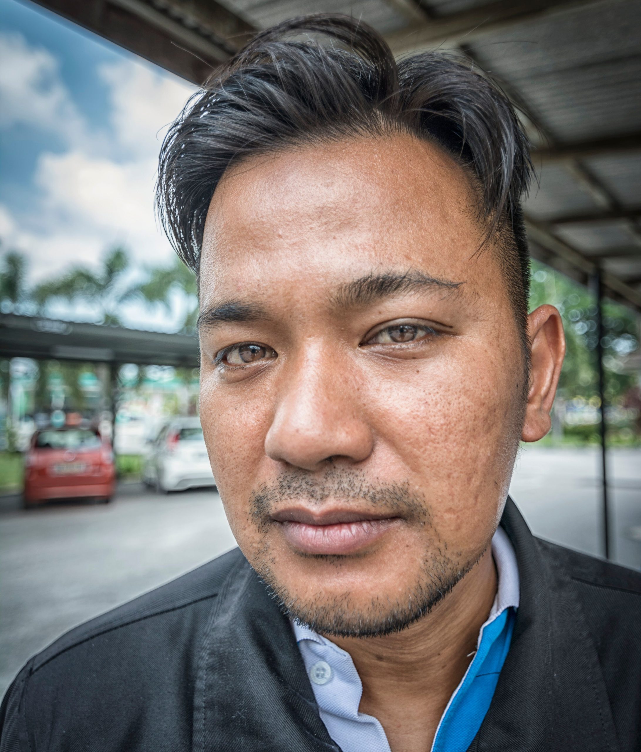 Close-up portrait of a young man outdoors on a sunny day with a serene expression.
